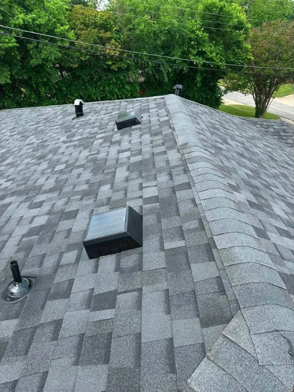 Close view of new gray architectural shingles with ridge vent and pipe boots
