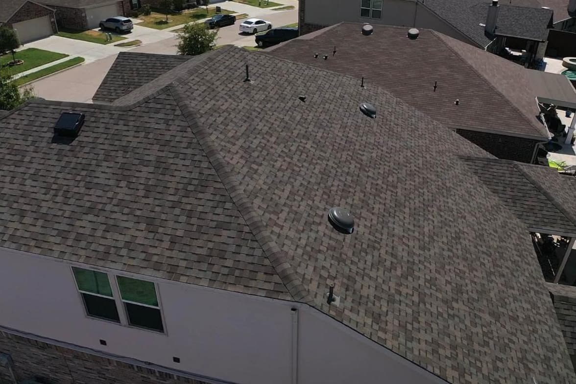 Aerial view of a large weathered-wood shingle roof after replacement